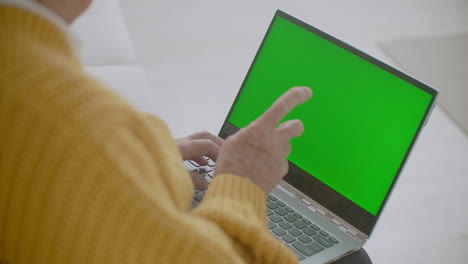 Grandmother-talks-looking-over-her-shoulder-looking-at-green-screen-with-chromakey